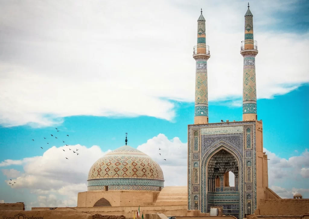نمای کلی مسجد جامع یزد با مناره‌های بلند و سردر کاشی‌کاری شده در بافت تاریخی شهر
